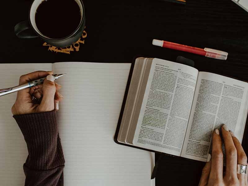 Hands taking notes from a Bible