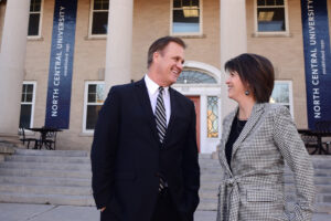 Former President Scott Hagan and Karen Hagan smiling by the TJ Jones library
