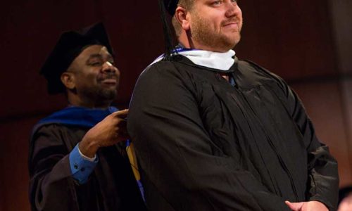 Professor bestowing a student with a tassel at a graduation ceremony.