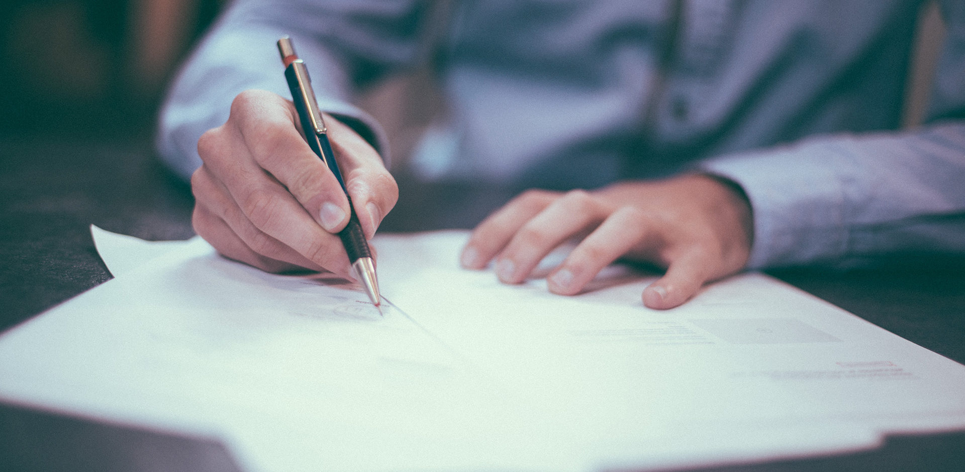 person writing on paper with a pen