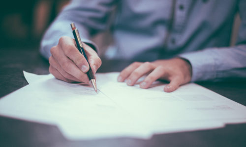 person writing on paper with a pen