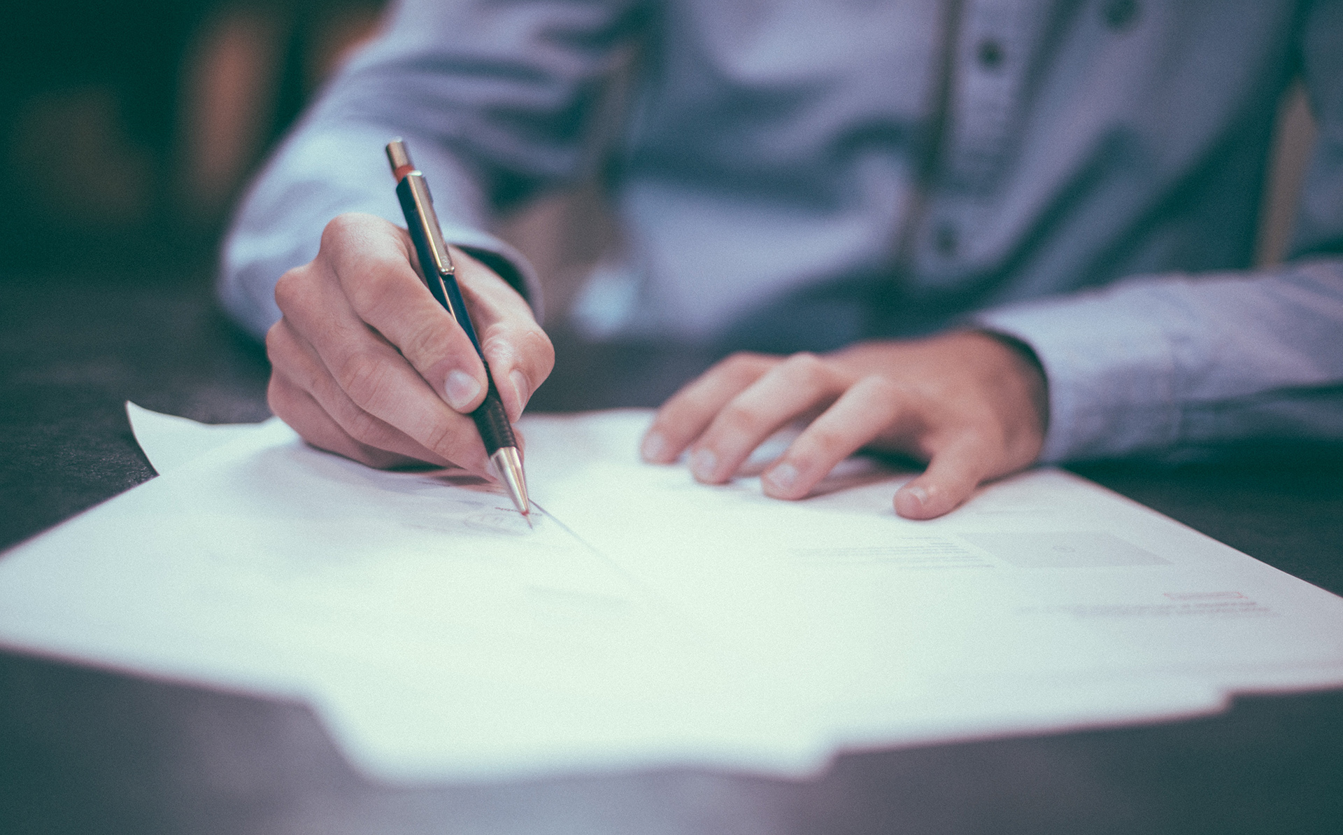 person writing on paper with a pen