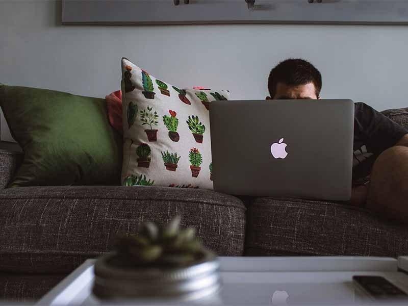 man on couch looking at laptop