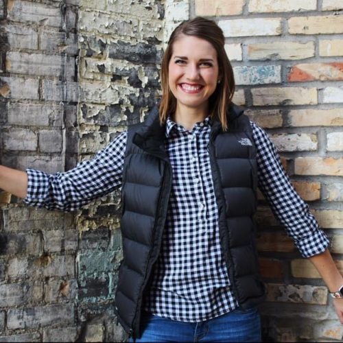 girl in plaid shirt in front of brick wall