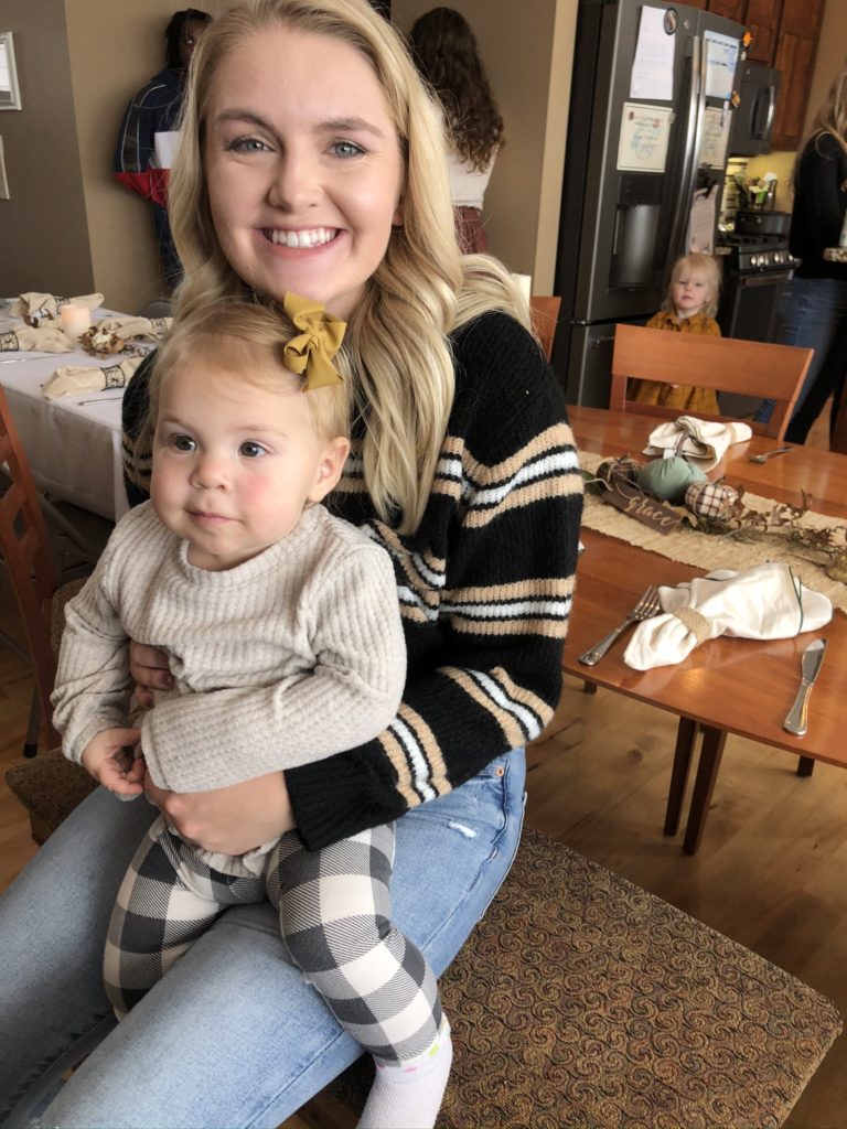 Woman holding a baby with a yellow bow