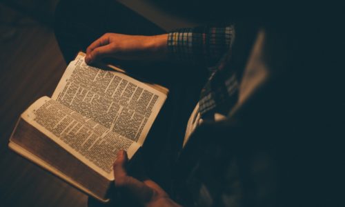 Person in dark reading a bible