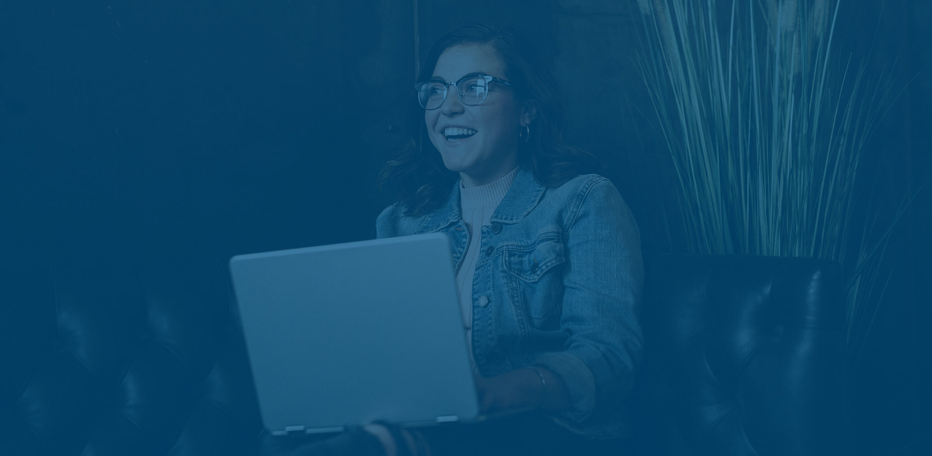 Online student using laptop on couch while laughing