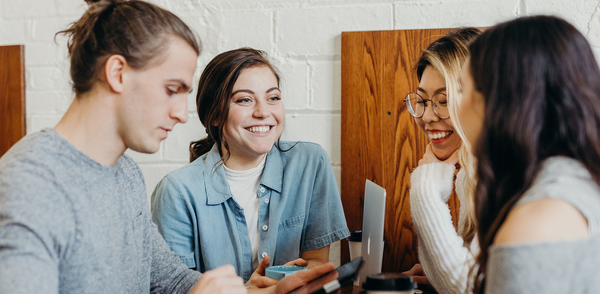 Group of four students talking to each other at a table