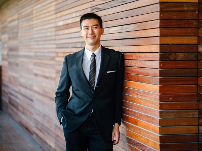 Person in suit leaning against a wall