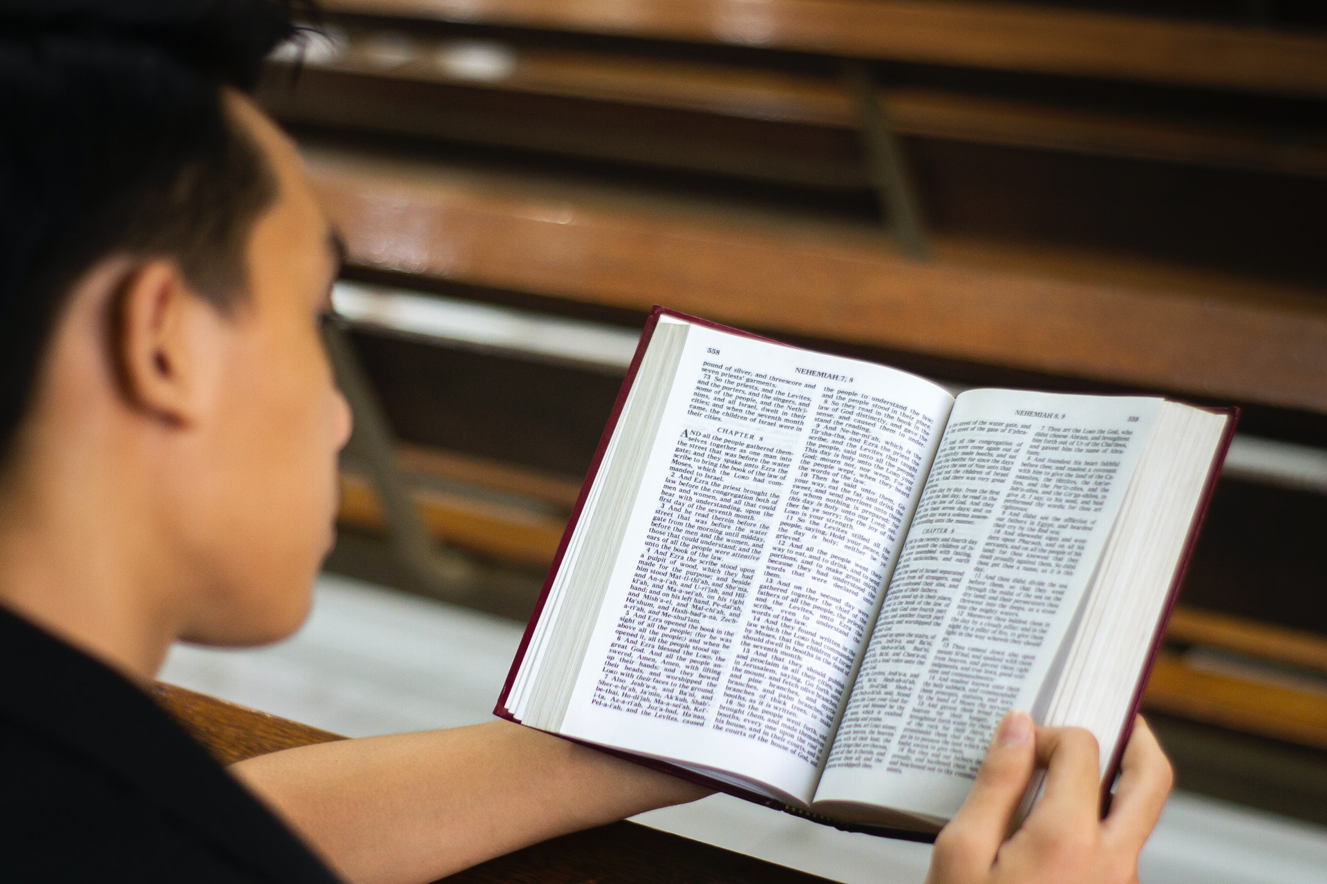 Man holding a bible leaning over a pew