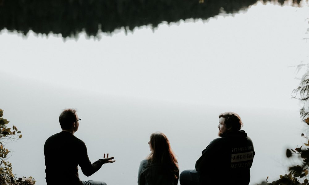 Three people having a conversation on a lake