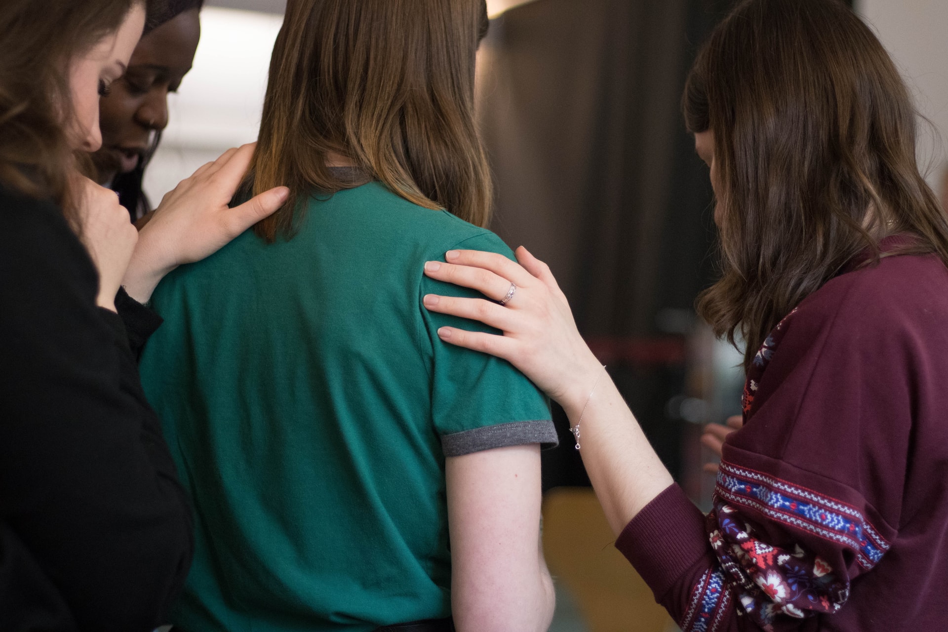 Two people laying hands praying for a girl