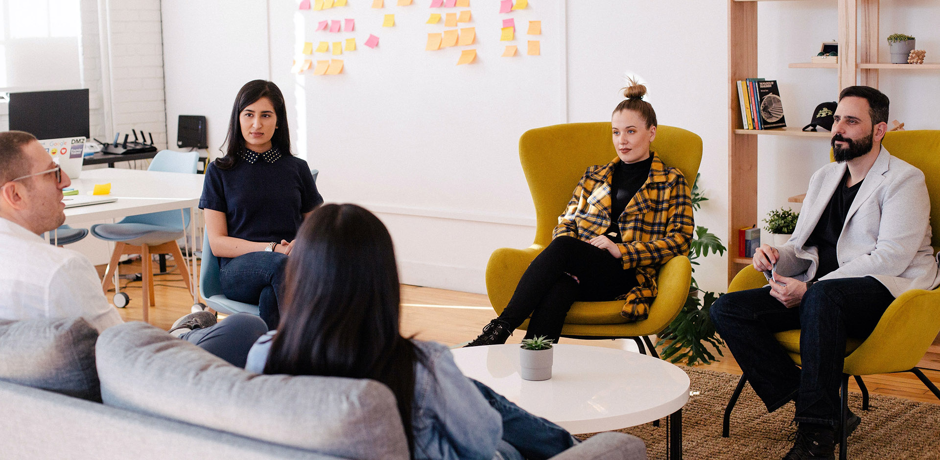 Group of young professionals sitting in a circle in a meeting.