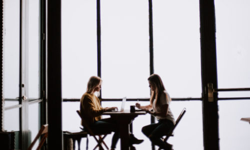 Two women sitting at a table having a meeting