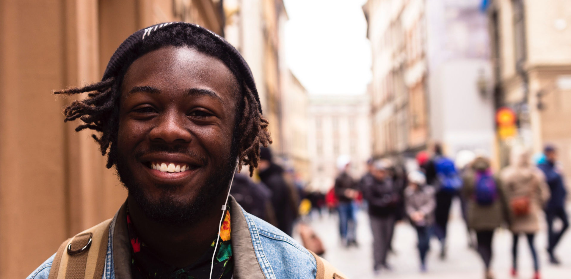 Man with earbuds smiling in the city