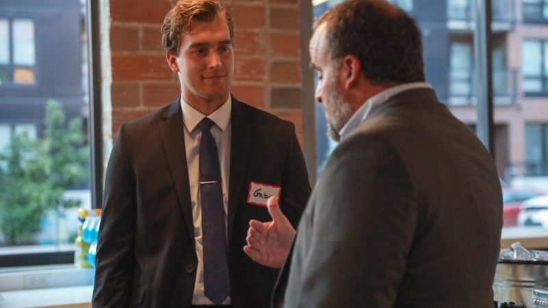 Two men in suits speak with each other