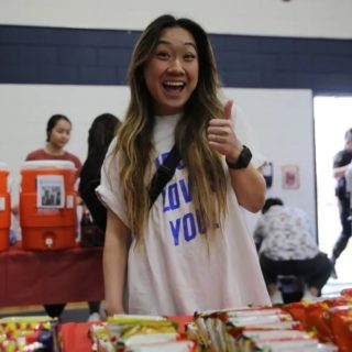 Student with thumbs up smiling at snack table