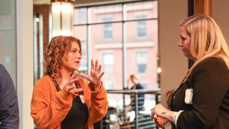 Two woman speak with each other at an event