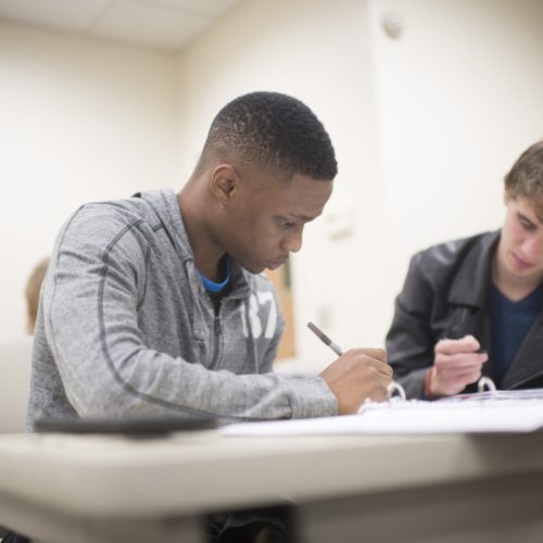 Two men sitting at a table work together on mathematics