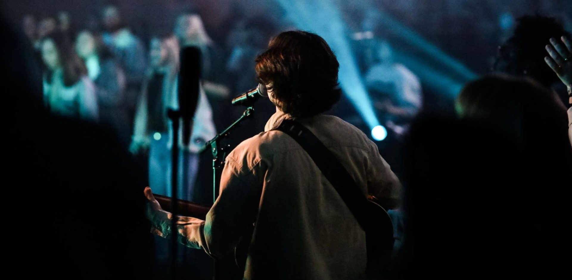 A man plays music and sings for a large audience