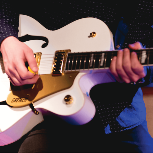 A man plays a white guitar during a live production