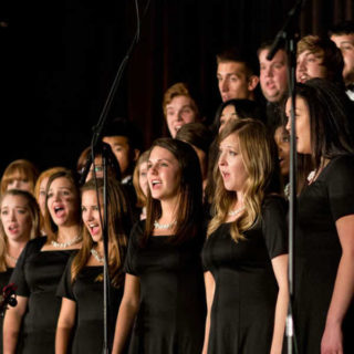 A choir sings as a condutor directs them