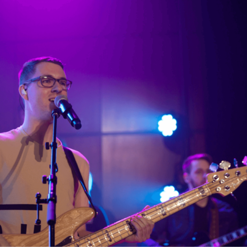 A man sings and plays bass during a group worship performance