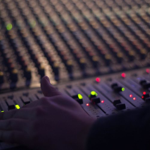 A man adjusts a slider on a mixing console