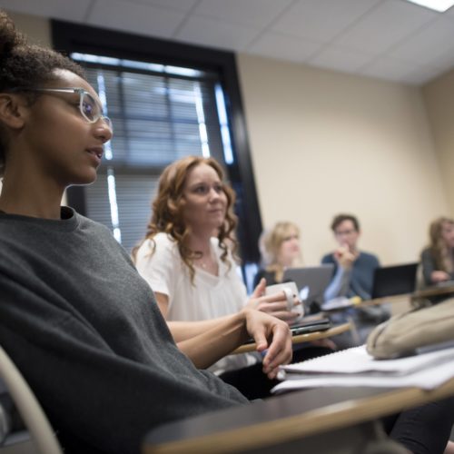 Several students sit in a classroom listening intently