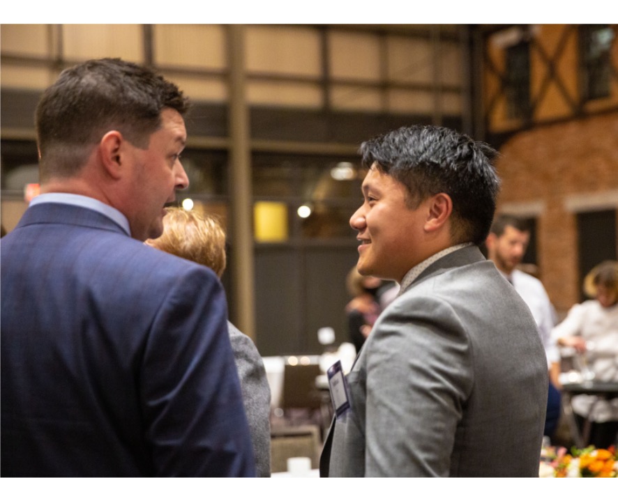 Two men speak with each other at a reception