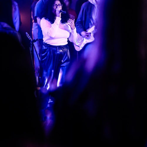 A woman sings on stage during a group worship performance