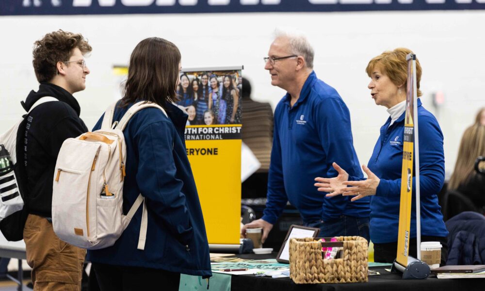 Two students speak with representatives for Youth For Christ International