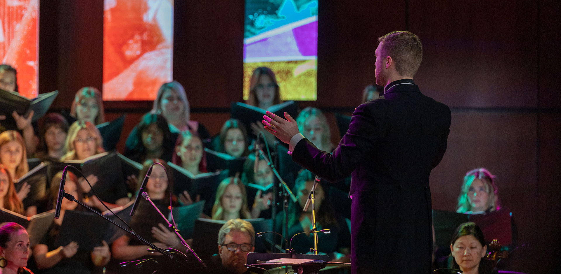 A man conducts an orchestra and choir