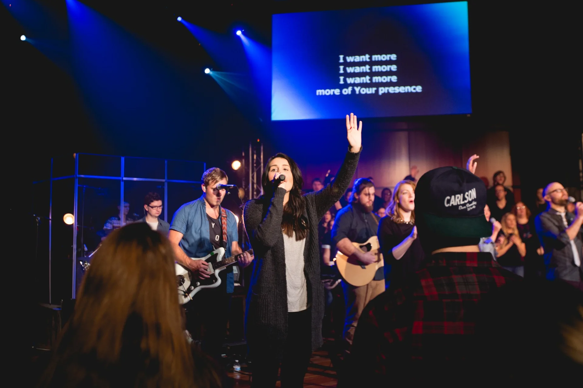 Students leading worship and singing on stage during a worship night at North Central University