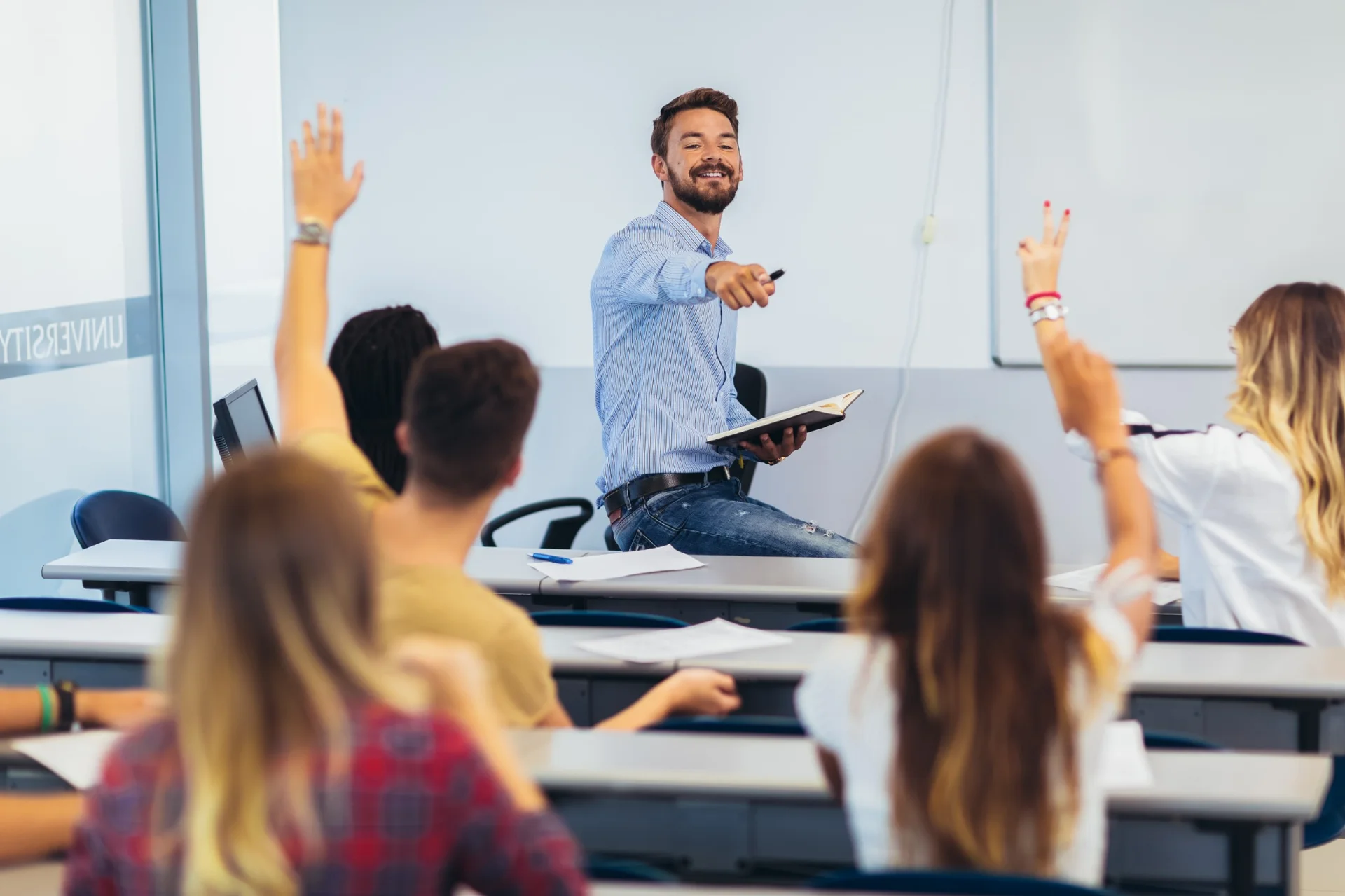 rofessor engaging with students raising hands in a university classroom at NCU
