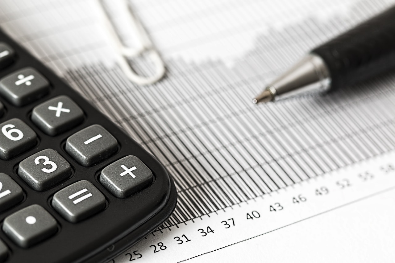 Photo of calculator, graph, paperclip, and pen
